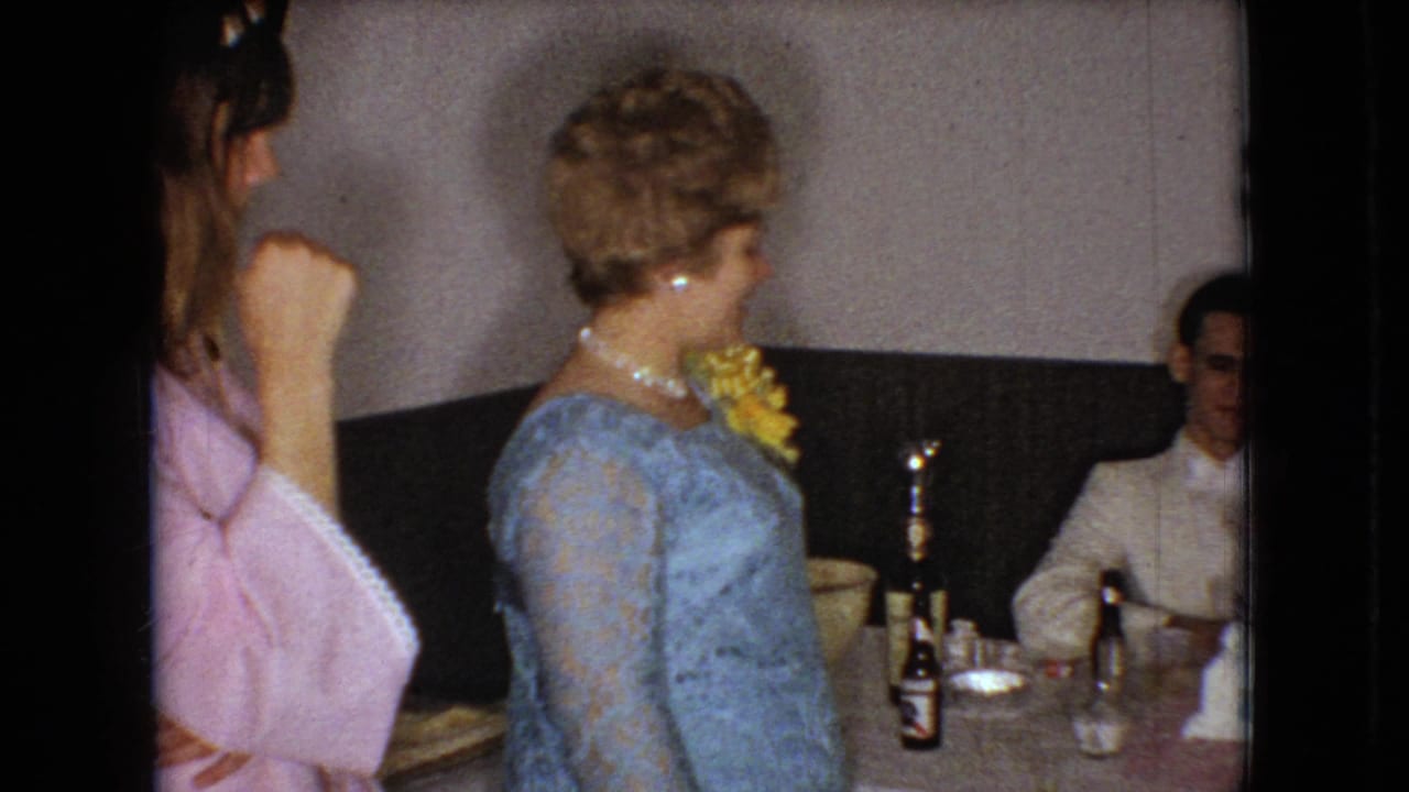 The 1966 Ohio reception scene shows the woman in a blue lace dress facing a man seated beside tableware, beer bottles, and a tiered cake, with another woman in pink partly visible at the left.