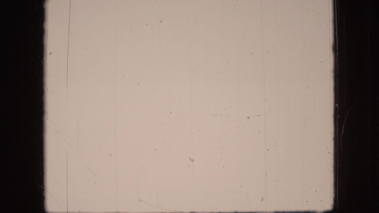 Pale overexposed film frame with scratches and dark frame borders.