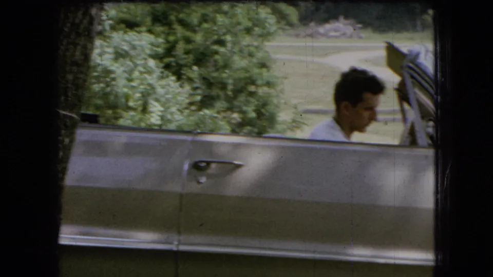 The final frame keeps the young man in profile in the open silver convertible, with leafy trees, grass, and a distant path behind the car.