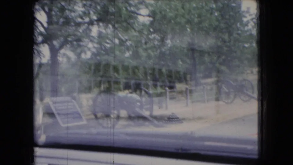 View through a car window toward a Civil War cannon display with trees, fencing, and roadside exhibit elements visible in the background.