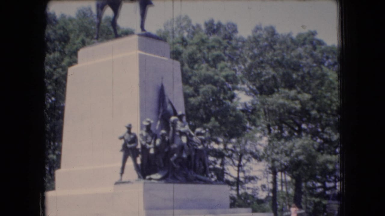 Stone monument with an equestrian statue and sculpted figures at its base.