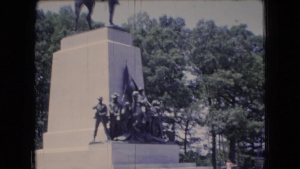 A wooded Ohio memorial scene shows a tall stone pedestal topped by an equestrian statue, with sculpted figures grouped near the base.
