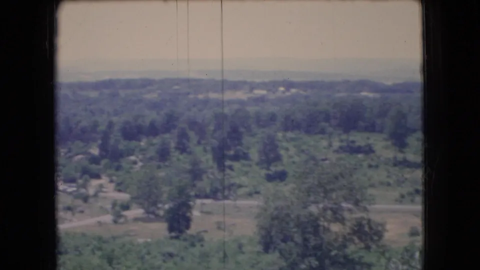 1966 Ohio home-movie frame showing a broad green and brown landscape with scattered trees, fields, a distant horizon, and visible 8mm film wear.