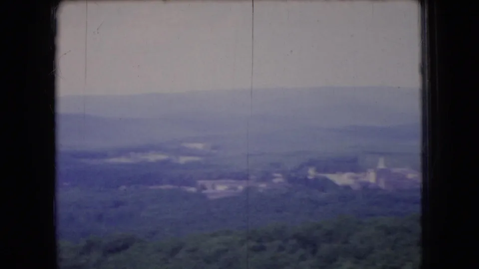 1966 Ohio 8mm frame showing hazy wooded hills, distant ridges, and soft valley detail through a dark window opening.