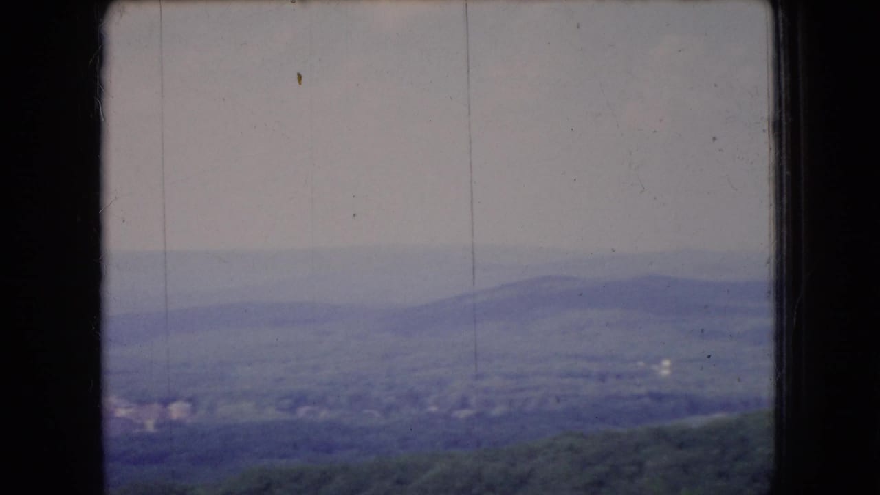 1966 Ohio 8mm view of layered hills and a hazy overcast horizon, divided by the dark edge of a window frame.