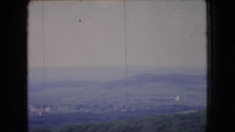 1966 Ohio 8mm view of layered hills and a hazy overcast horizon, divided by the dark edge of a window frame.