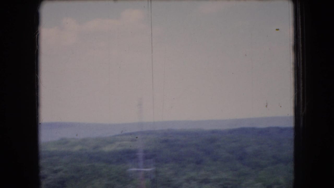 1966 Ohio 8mm frame showing distant rolling forested hills under a pale, cloudy morning sky, with soft focus and faded color.
