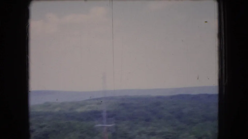 1966 Ohio 8mm frame showing distant rolling forested hills under a pale, cloudy morning sky, with soft focus and faded color.