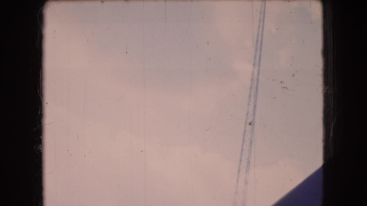 1966 Ohio 8mm frame showing a pale hazy sky through dark window-frame borders, with a diagonal structural shadow and a thin vertical cable line.