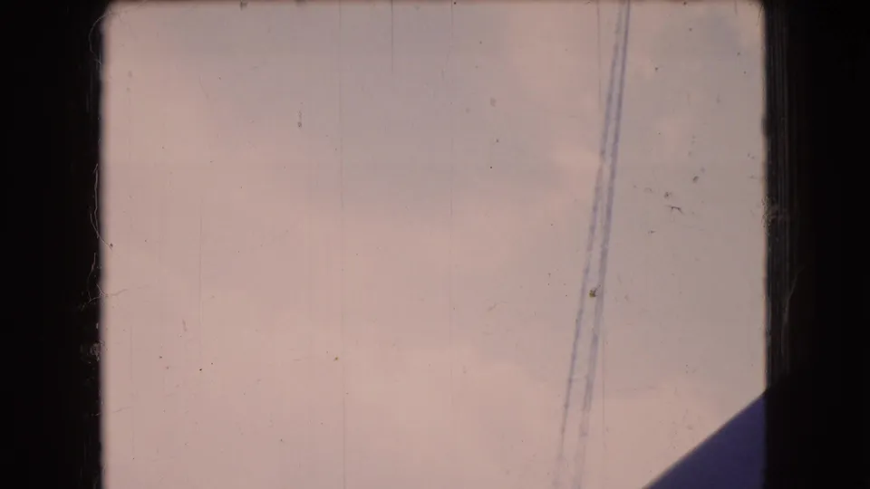 1966 Ohio 8mm frame showing a pale hazy sky through dark window-frame borders, with a diagonal structural shadow and a thin vertical cable line.