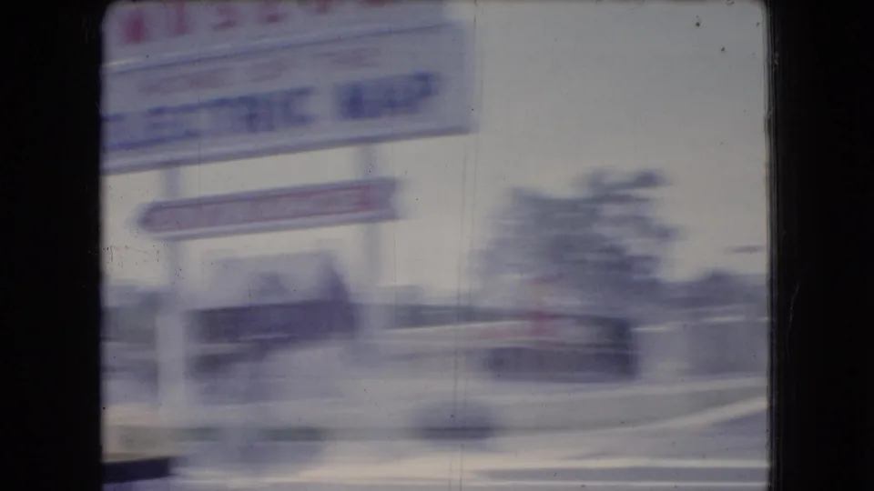 Passing view of a Gettysburg National Museum sign referencing the Electric Map, with nearby roadside structures blurred by car movement.