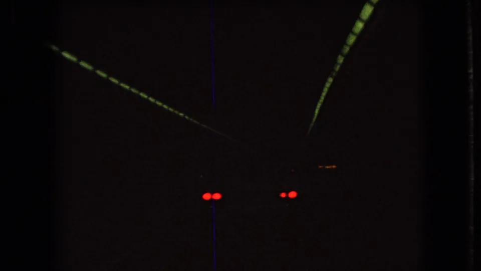 Inside the tunnel, the car is mostly lost in shadow, leaving red taillights and faint overhead light streaks visible against the dark 8mm frame.