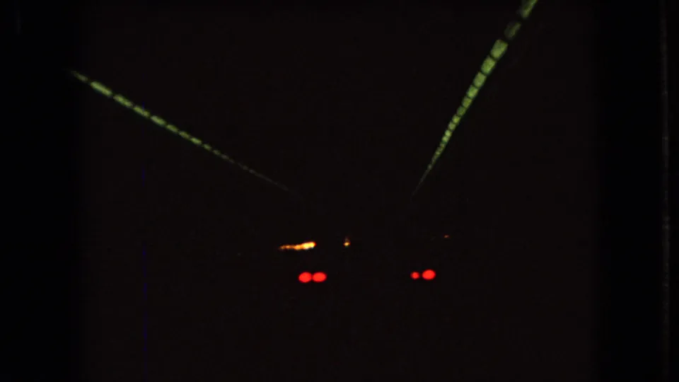1966 Ohio 8mm home-movie frame showing a car from behind in a dark tunnel, with red taillights and converging tunnel lighting.
