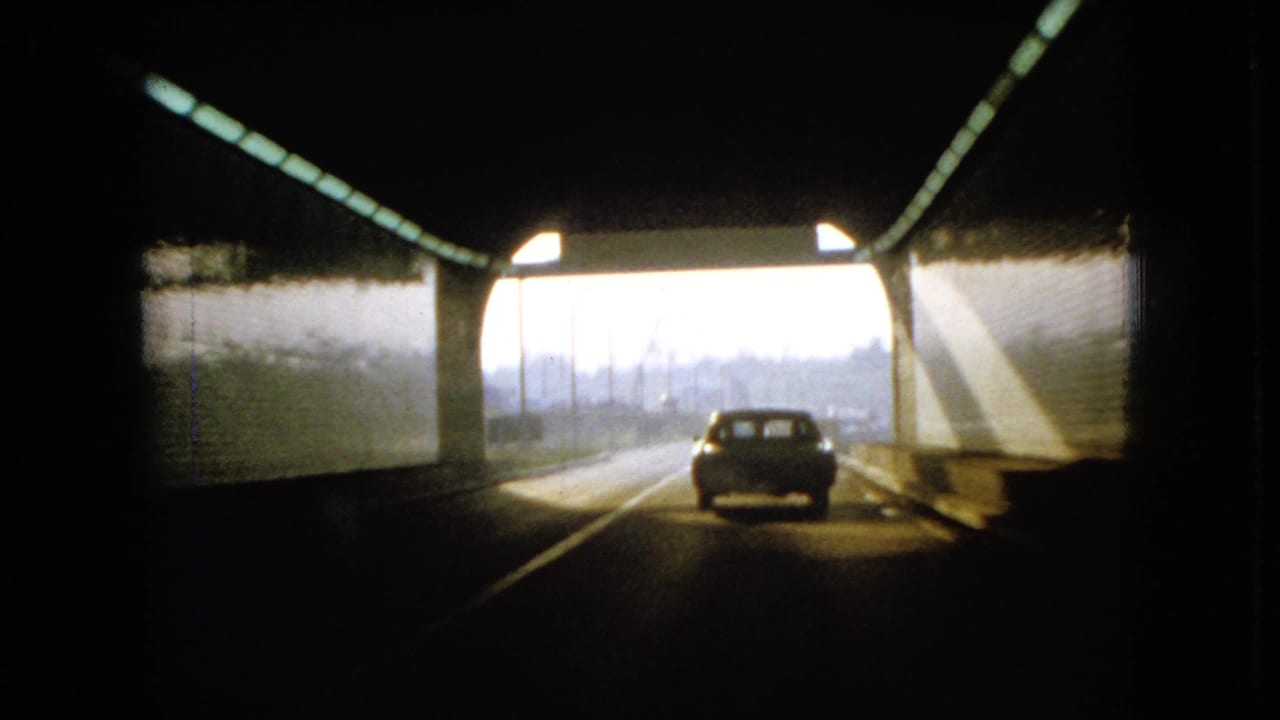Car drives toward daylight at the end of a tunnel.