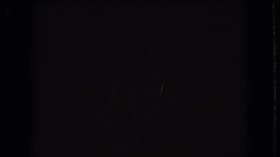 A dark 8mm contact-frame view shows only a partial lower strip of a 1966 Ohio house under construction, with pale sheathing and trees just visible.