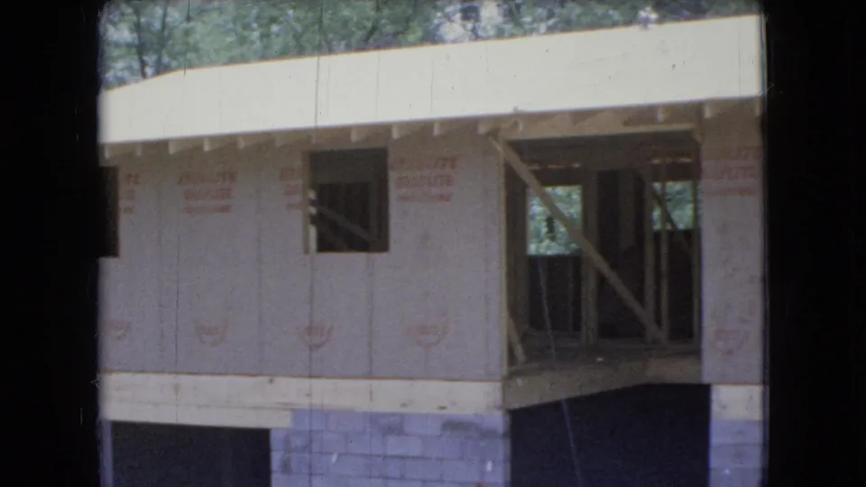 A 1966 Ohio construction view shows a residential wall with exterior sheathing, an open framed section, diagonal bracing, concrete-block foundation, and wooded background.