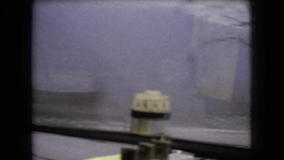 Interior car view from a 1966 Ohio home movie, showing a small dashboard instrument against a pale snowy landscape and bare winter trees outside.