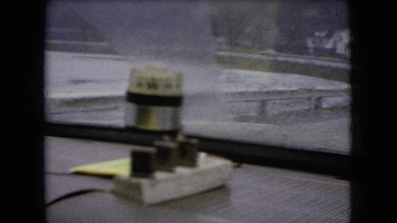 Dashboard device silhouetted against a rainy bridge or roadway seen through the windshield.