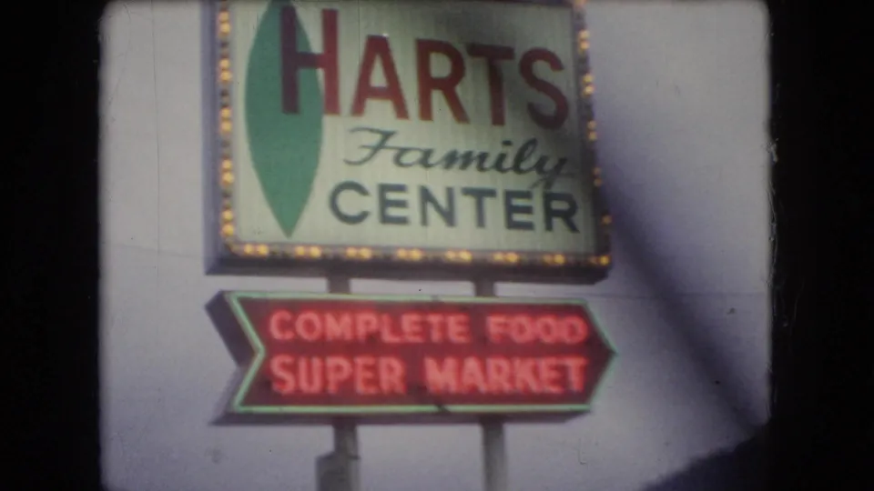 Roadside Harts Family Center sign with a red Complete Food Super Market arrow sign below, filmed in 1966 Ohio home-movie footage.