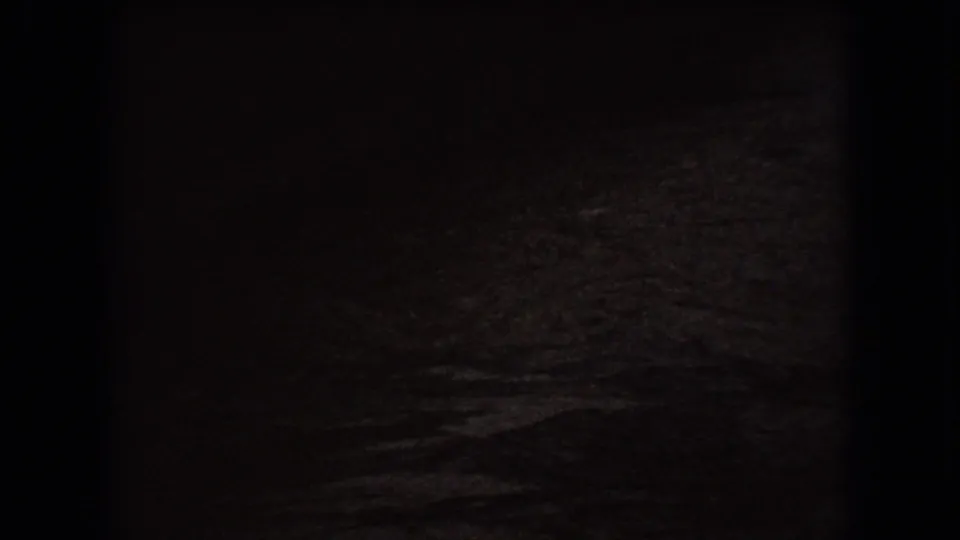 Dark final 1966 Ohio frame showing a shadowed ground or roadway surface with grainy texture and minimal identifiable detail.