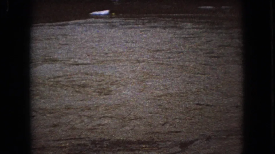 A dimly exposed water surface fills the 1966 Ohio frame, showing ripples, soft grain, and a small pale reflection near the top edge.