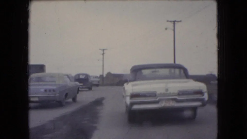 1966 Ohio road scene with a white convertible, another pale car, and darker automobiles traveling away from the camera on an overcast day.