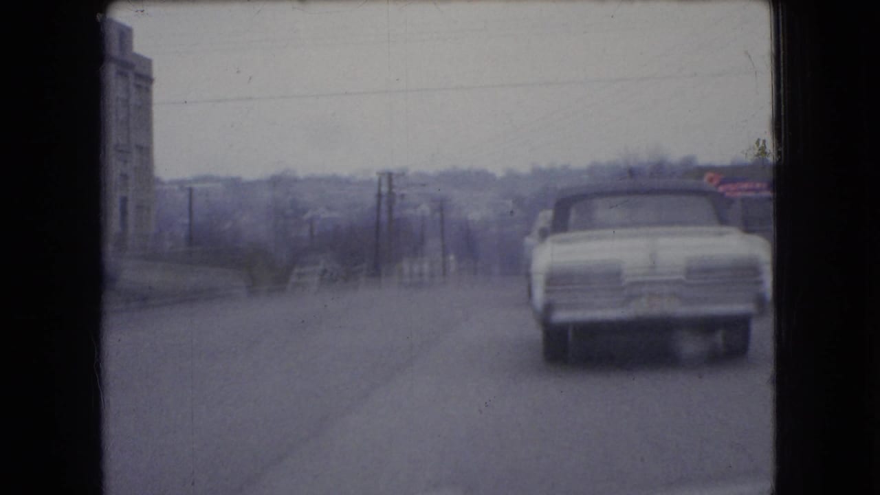 White car farther down the road with buildings and poles along the roadside.