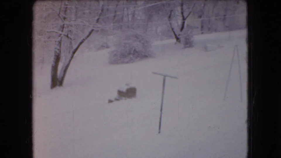 The final frame holds on a quiet snow-covered yard or slope in 1966 Ohio, with bare trees, a small brick object, and a simple pole or frame visible in the foreground.