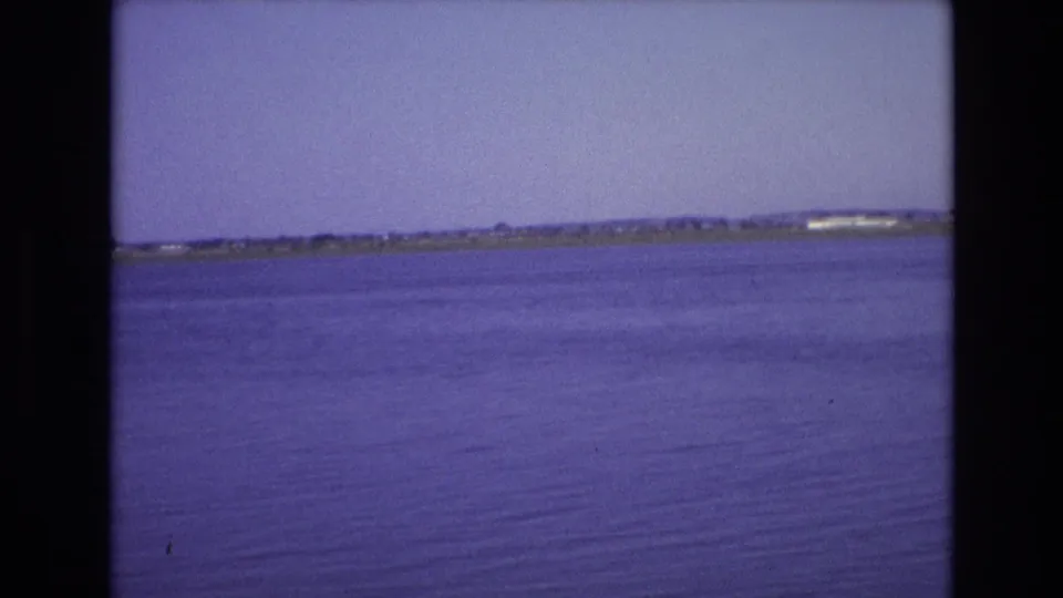 1972 Portugal 8mm frame showing open blue water and a distant low shoreline under a clear sky after the small boat has passed out of frame.