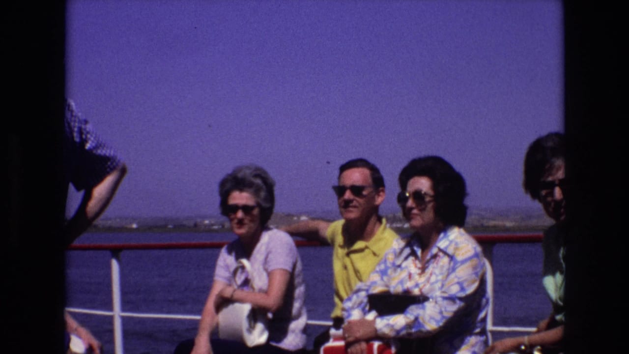 Three adults face the camera near a ship railing with water in the background.