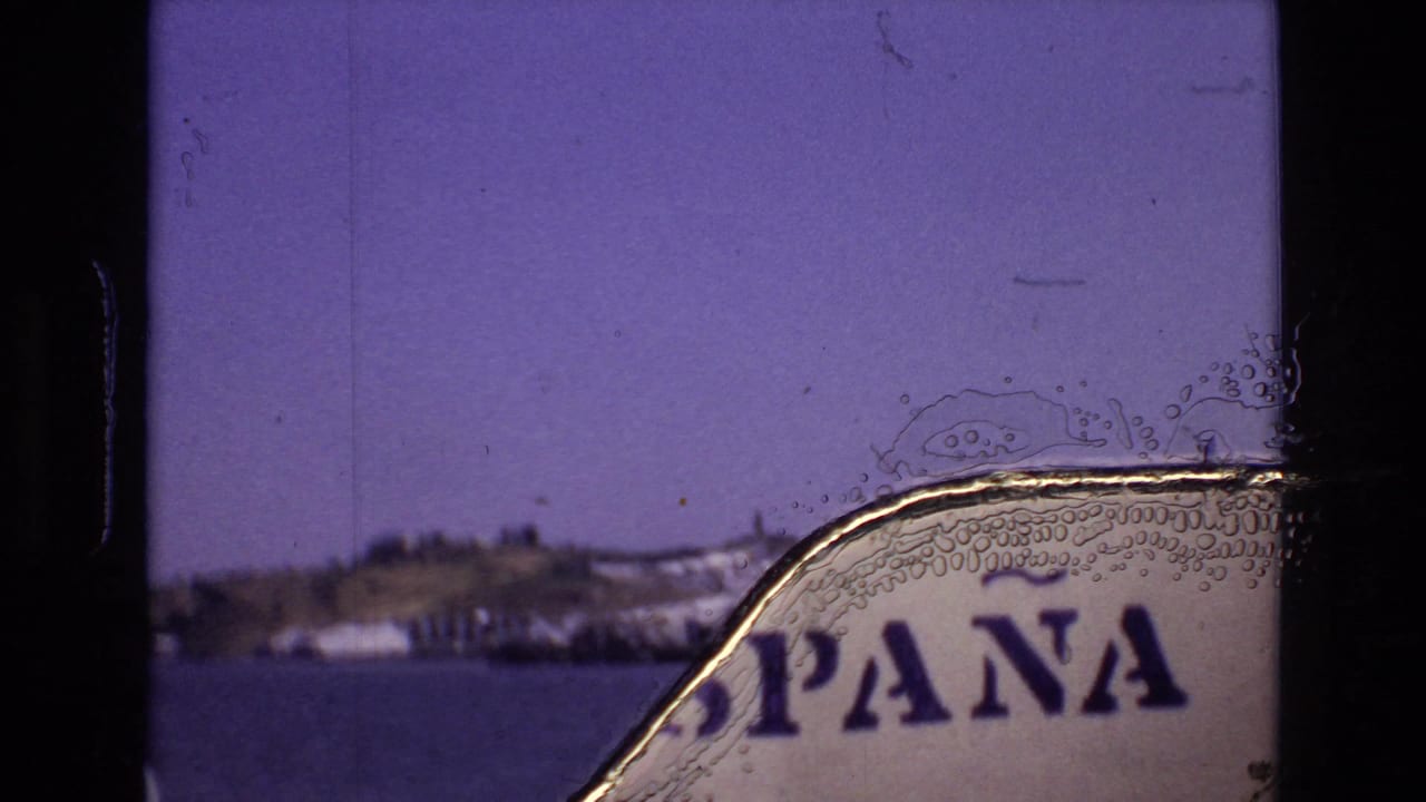 Waterfront hillside view partly obscured by a torn or bubbled film-edge artifact and partial lettering.