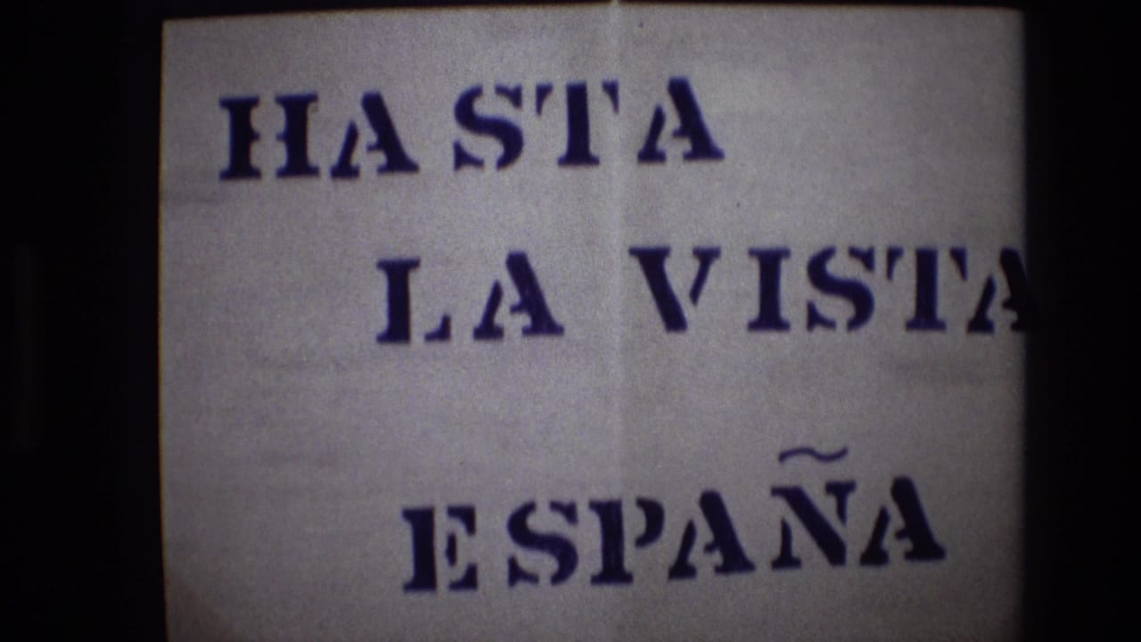 White paper sign with blue stencil text reading HASTA LA VISTA ESPAÑA.