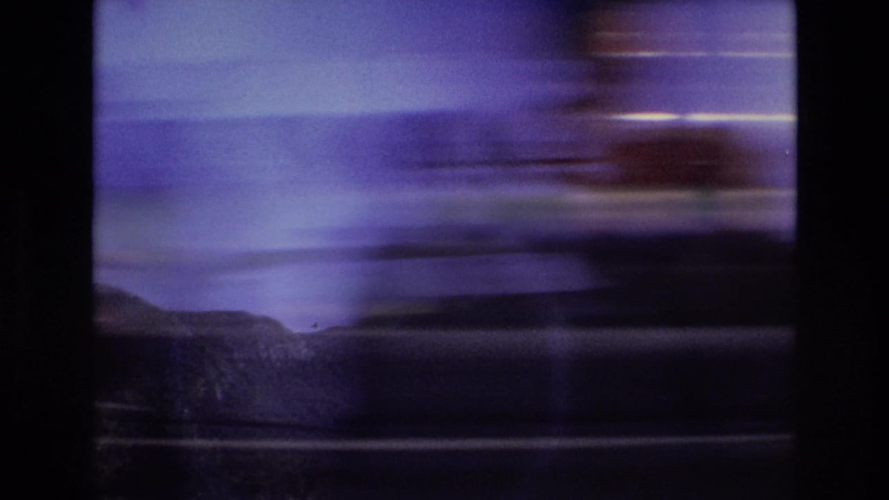 1972 Portugal home-movie frame showing a fast-blurred roadside view through dark vehicle or window framing, with distant mountain ridges partly visible.
