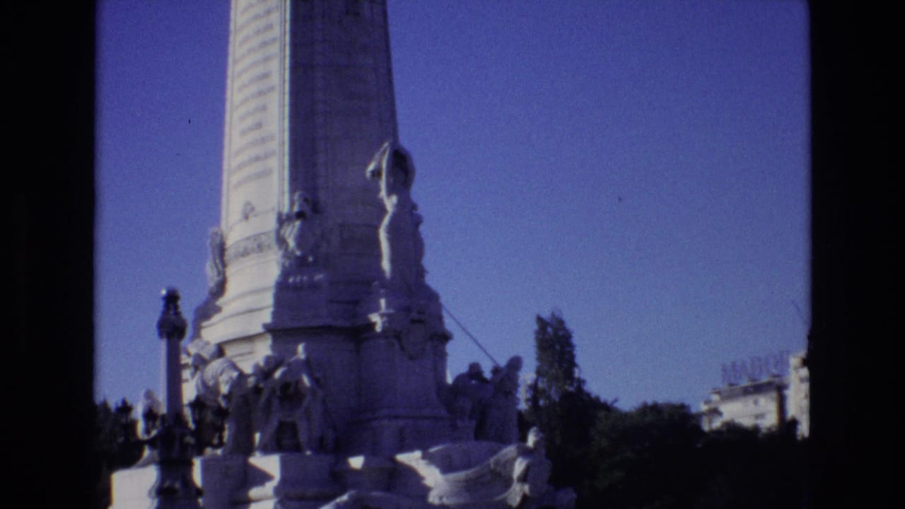 Tall stone monument with statues at the base and trees behind it.