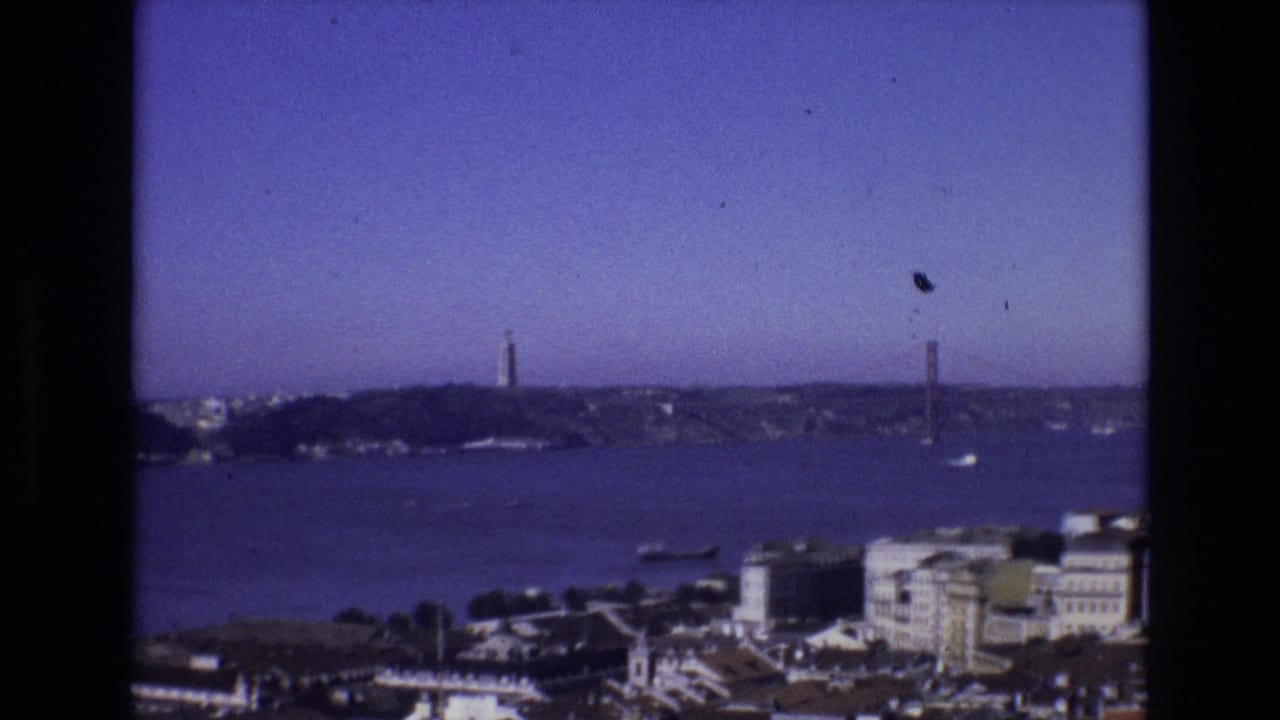 Lisbon, Portugal, in 1972 seen from an elevated tourist viewpoint, with the Tagus River, Torre de Belem, boats, and the suspension bridge across the frame.