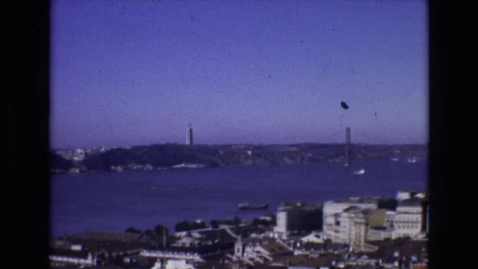 Lisbon, Portugal, in 1972 seen from an elevated tourist viewpoint, with the Tagus River, Torre de Belem, boats, and the suspension bridge across the frame.