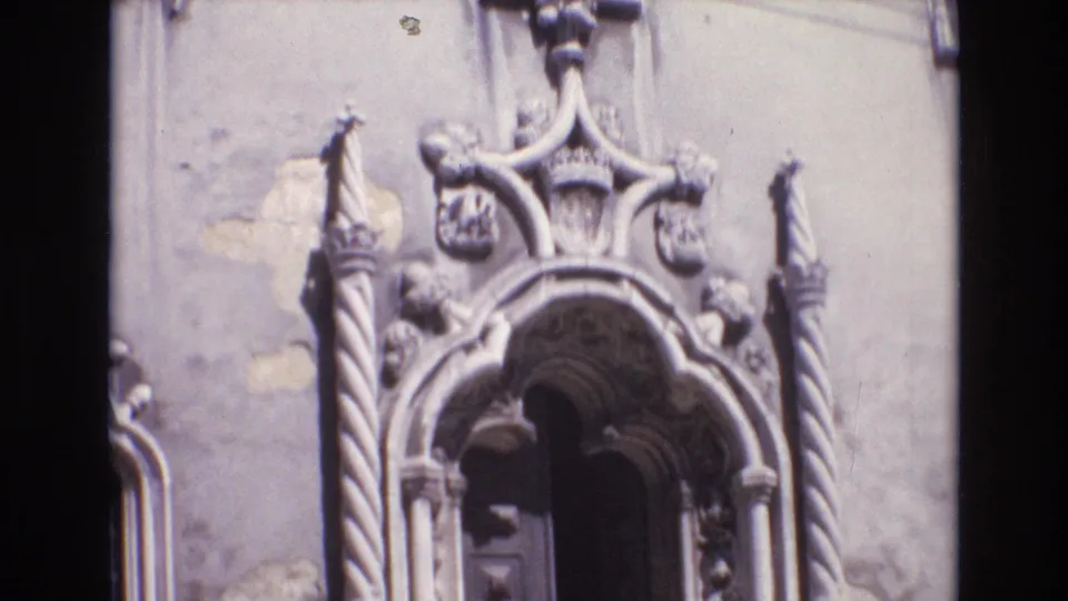 1972 Portugal 8mm frame showing an ornate arched stone entrance with carved columns and decorative relief against a weathered exterior wall.