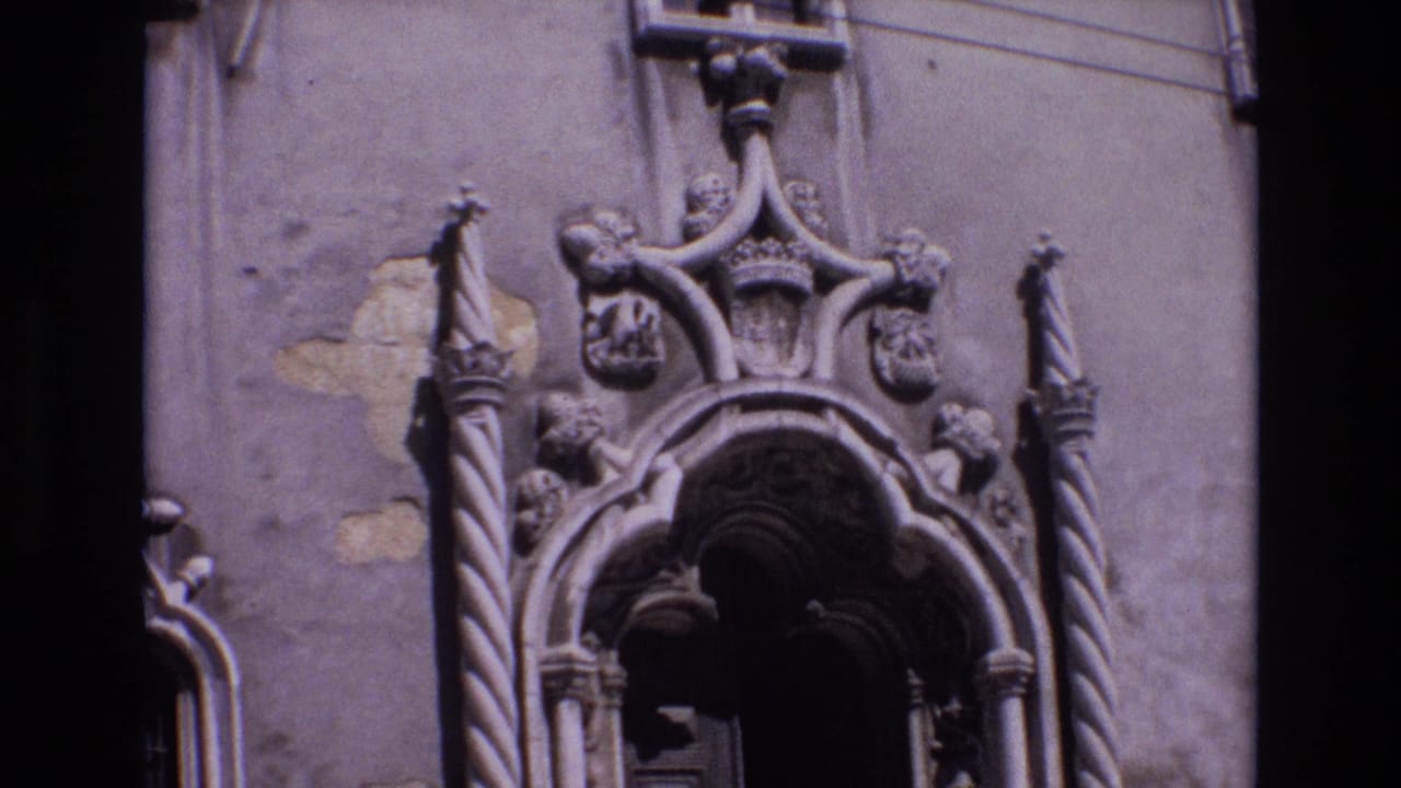 1972 Portugal 8mm frame showing the upper portion of an ornate Baroque church entrance with twisted columns, carved shields, and a dark arched doorway.