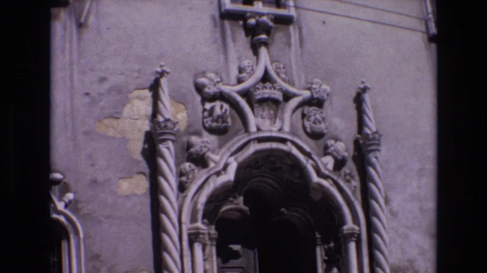 1972 Portugal 8mm frame showing the upper portion of an ornate Baroque church entrance with twisted columns, carved shields, and a dark arched doorway.