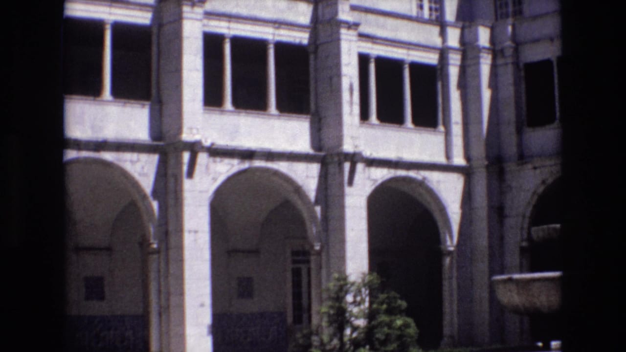 1972 Portugal 8mm frame with repeated stone arches, rectangular windows, shaded doorways, and a dark foreground strip from the camera position.