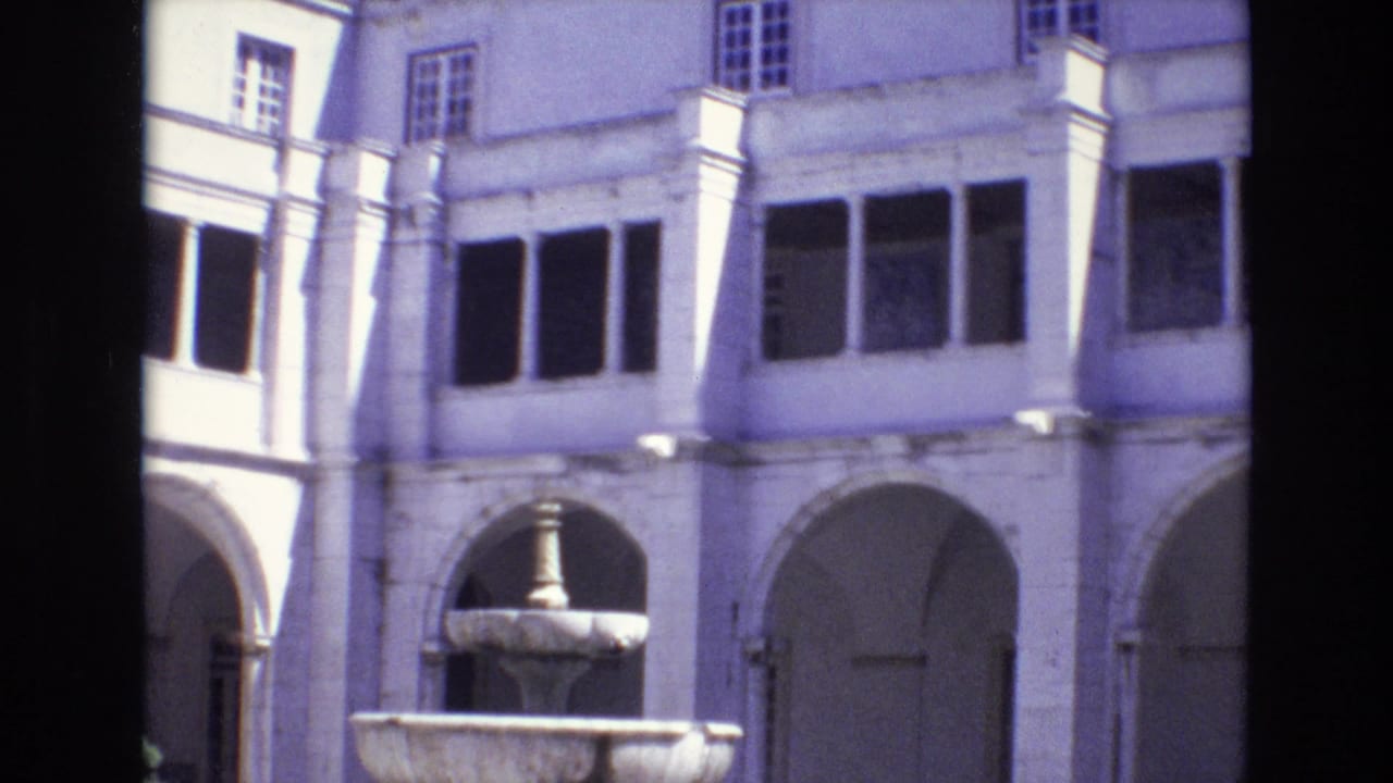 Courtyard building facade with a fountain, arches, columns, and rows of windows.