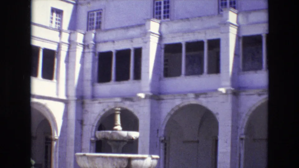 1972 Portugal frame of a historic courtyard facade, with a stone fountain in the foreground and arched walkways beneath upper windows.
