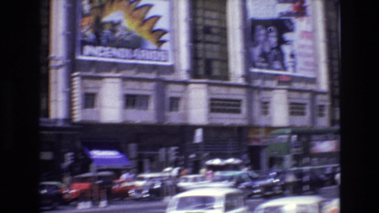 1972 Portugal street view with large cinema posters, parked and moving cars, a bus, and pedestrians near the theater frontage.