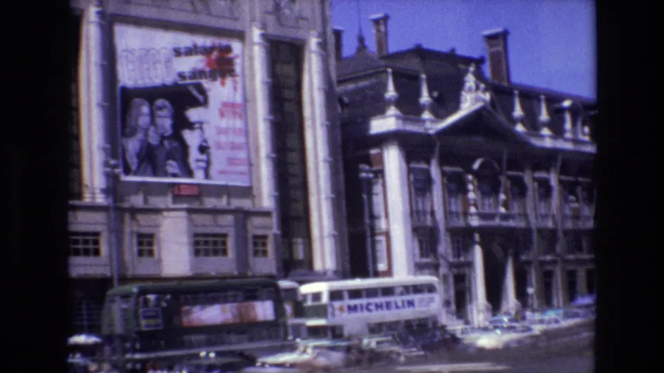 1972 Portugal 8mm frame showing a cinema facade with large poster signage, a Michelin-branded bus, pedestrians, and cars along the street.