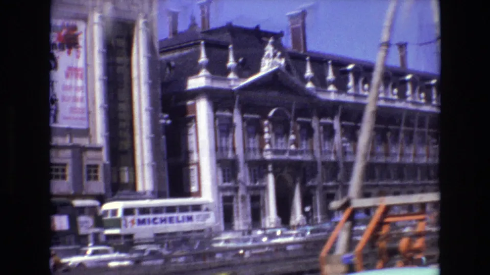1972 Portugal city street frame with an ornate cinema or theater frontage, white bus, cars, and a partially visible orange vehicle in traffic.