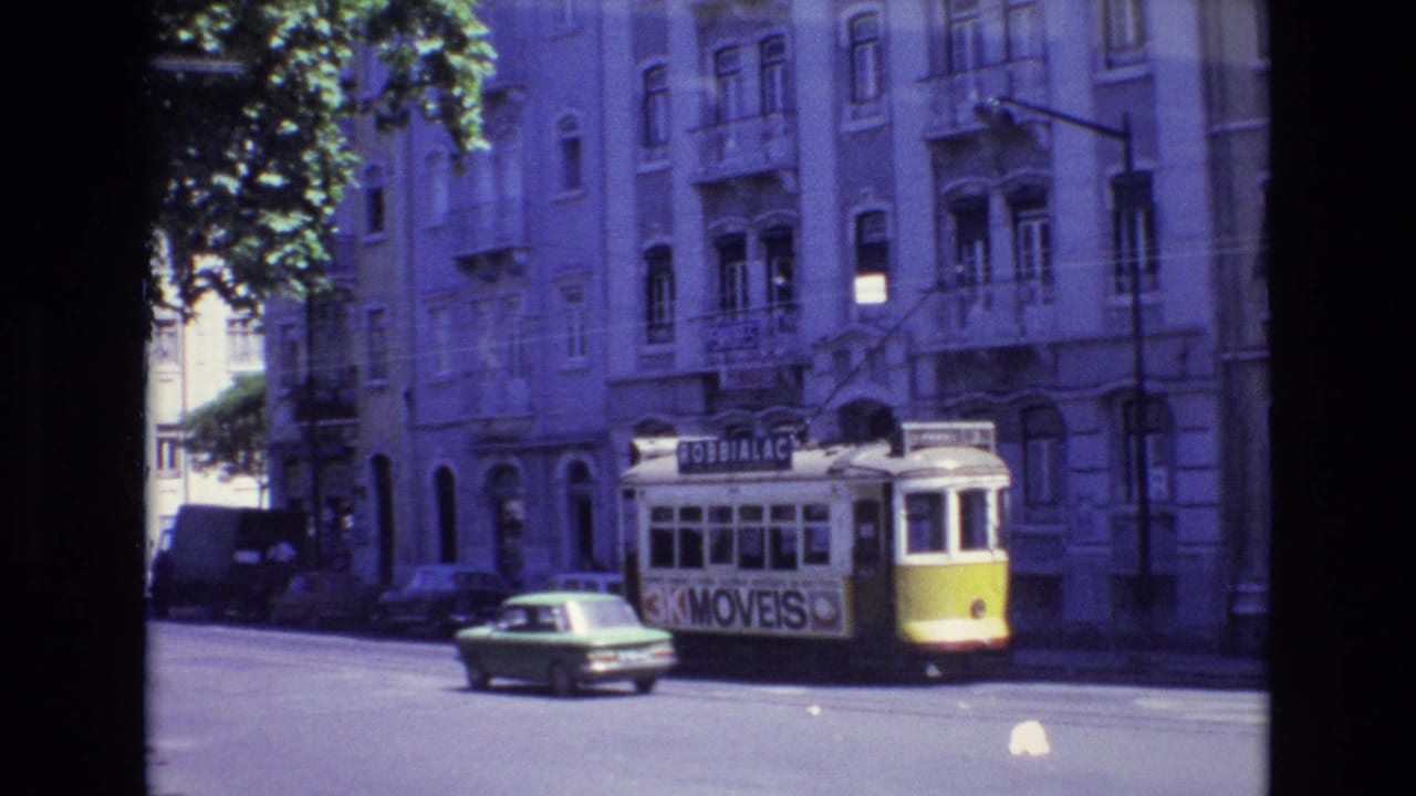 1972 Portugal 8mm frame showing a yellow-and-white trolley with advertising signage moving along a shaded urban street beside apartment buildings and traffic.
