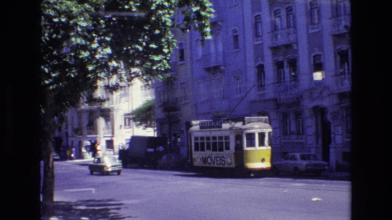 1972 Portugal street view with a yellow-and-white trolley traveling past parked cars, leafy shade, and multi-story residential buildings.