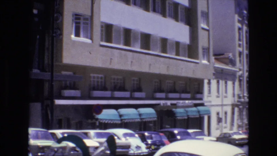 The final frame shifts to a wider Portugal 1972 city street view with parked cars, a white Beetle-like car, multi-story facades, green awnings, and a no-parking sign.