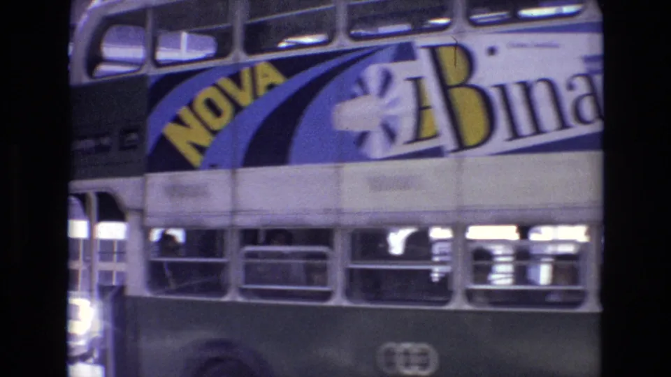 The final frame holds a close view of the bus side advertisement and lower windows as the double-decker passes through the Portugal street scene.
