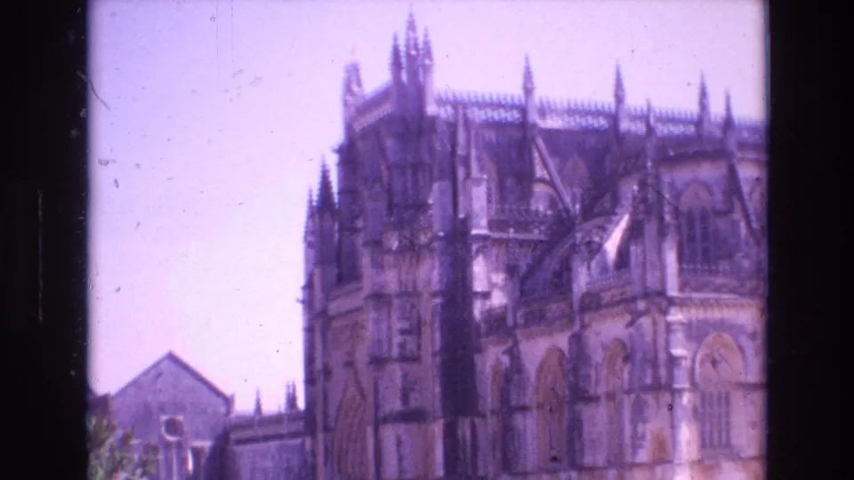 1972 Portugal travel frame showing a large Gothic-style stone building with pointed spires, arched windows, and a bright pale sky.